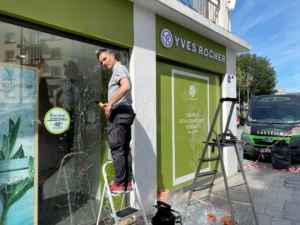Pose d’un film anti graffiti sur la devanture d’une boutique de soins à Caen, avec le véhicule Easy Film en arrière-plan