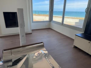 Rouleau de film miroir Easy Film prêt à poser dans le séjour d’une maison face à la mer, avec vue sur le large préservée