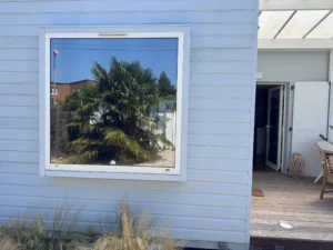 Fenêtre d’une résidence secondaire à Jullouville équipée d’un film solaire effet miroir posé par Easy Film, reflétant le jardin sans laisser voir l’intérieur